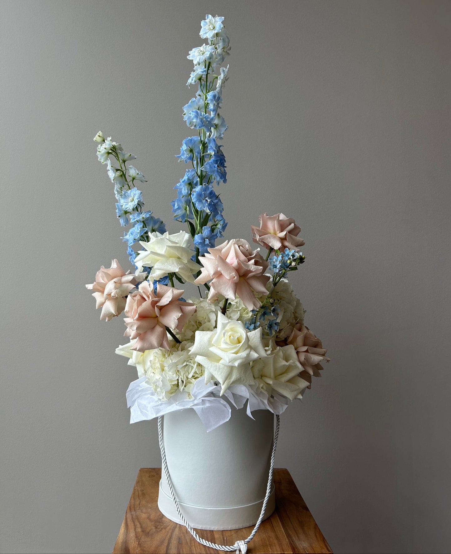 Floral arrangement in a white box on a pedestal against a grey background