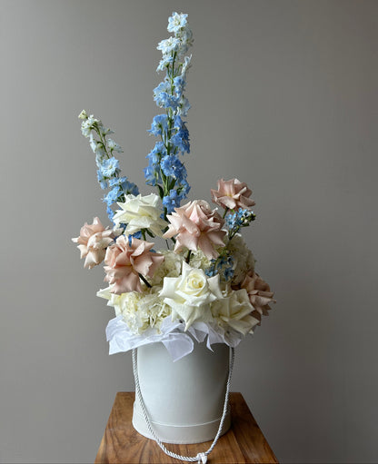 Floral arrangement in a white box on a pedestal against a grey background